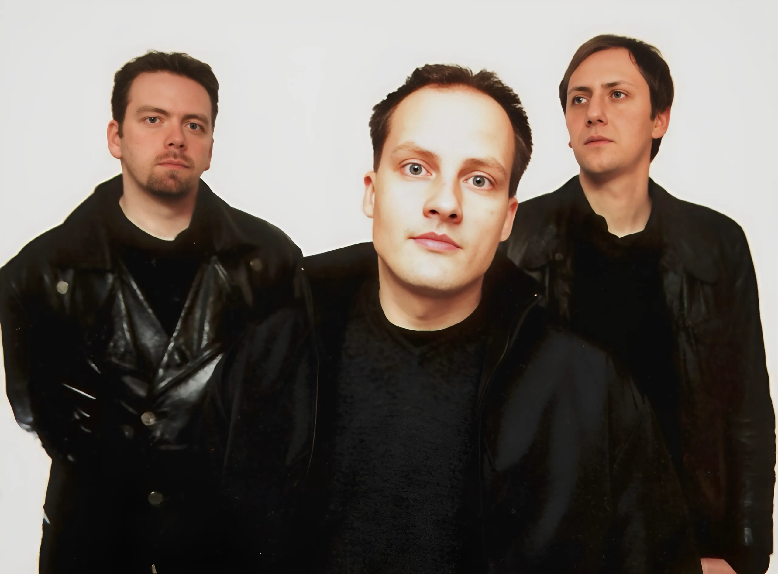 Bandfoto: drei Männer in schwarzen Jacken vor hellem Hintergrund